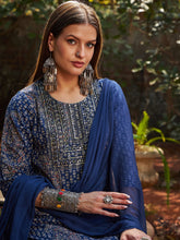 قميص نسائي أزرق داكن مزين بنقوش زهرية على الصدر، مع بنطال ضيق وشال.